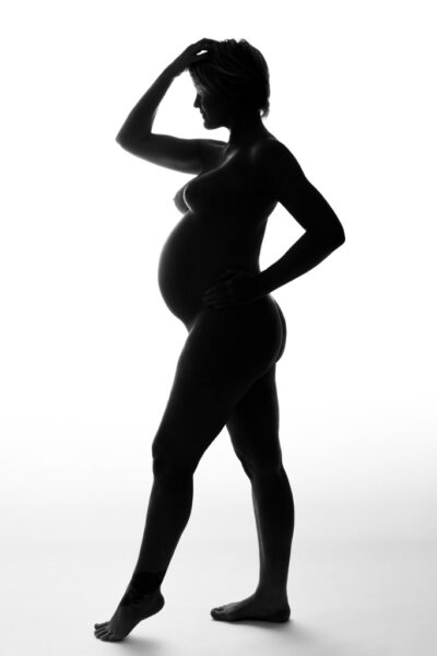 Grafisk silhuet af nøgen gravid kvinde i profil mod hvid baggrund